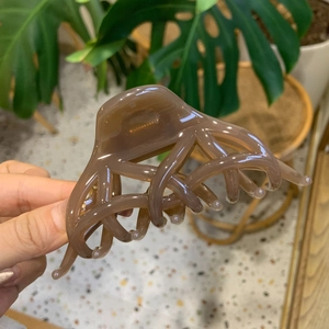 Vista dettagliata della grande clip per capelli marrone ambra con molla e denti multipli