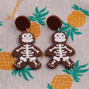 Detailed view of gingerbread man earrings with white skull prints on a patterned fabric