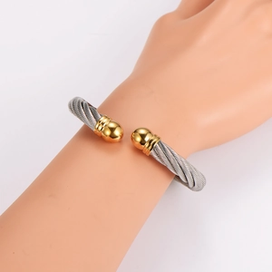 Two-tone stainless steel cable wire cuff bracelet with silver and gold finish on model