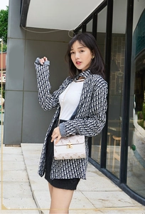 Close-up of white crossbody bag with gold metal lock and monogram pattern detailing