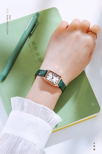 Retro square gold watch with green crocodile leather strap worn on wrist with pen