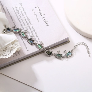 Detail of silver swan bracelet featuring colorful abalone shell inlays on an open book