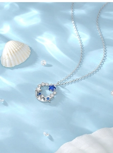 Macro detail of S925 sterling silver star pendant with blue stones on water ripple backdrop