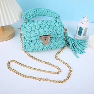 Détail du sac bandoulière crocheté vert menthe avec texture tricotée grossière et chaîne dorée.
