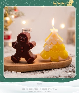 Detail of gingerbread man and Christmas tree scented candles on a wooden tray
