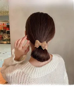 Close-up of a beige velvet bow hair scrunchie worn on a ponytail for a stylish hair look
