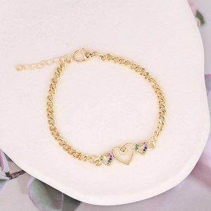Macro detail of gold-plated chain bracelet with colorful zircon heart charms on stone