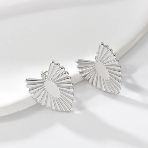 Detailed close-up of heart-shaped silver earrings featuring unique radial metal textures