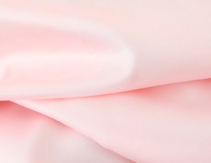 Detailed macro view of the silky pink fabric texture and elegant pleated satin folds