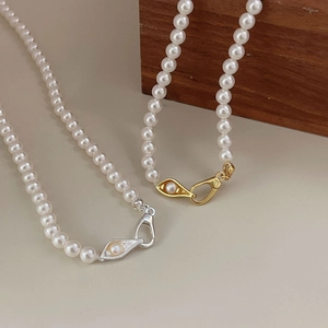 Detailed view of artificial pearl necklace with vintage gold and silver clasps