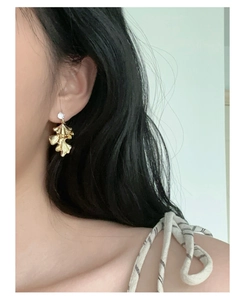 Macro view of gold leaf pendant earring with silver needle and sparkling crystal detail