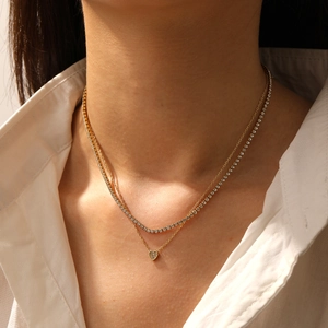 Close-up of double-layer gold necklace featuring heart pendant and tennis chain detail
