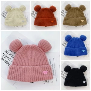 Detail of knitted beanie with bear ears and heart patch in six vibrant color options