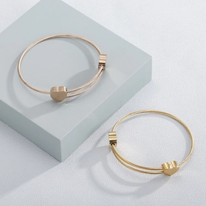 Detail of adjustable heart charm wire bracelets in gold and rose gold finishes