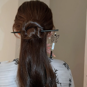 Detail of butterfly tassel hair pin with white pendant shown in an elegant updo hairstyle