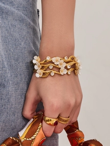 Detailed shot of a gold-plated flower bangle with sparkling cubic zirconia on a wrist