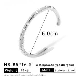 Détail du bracelet rigide en acier argenté avec texture ondulée, perles et strass
