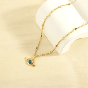 Macro view of gold-plated evil eye necklace with blue gemstone detail on white fabric