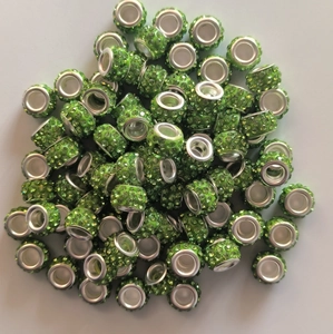 Close-up of green crystal clay beads with silver eyelets for DIY jewelry making