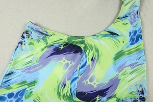 Détail de l'imprimé abstrait coloré sur une combinaison asymétrique aux tons vert et bleu