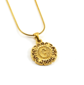 Vue macro du pendentif rond lettre G doré avec design ajouré sur chaîne serpent fine