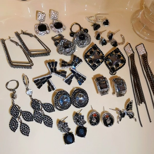 Silver needle earrings collection with black cubic zirconia and tassels on beige background
