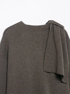 Detail of dark brown knitted poncho showing neckline texture and draped shoulder scarf scarf
