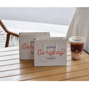 Detail of white paper gift bags with Everyday print on a rustic wooden table setup