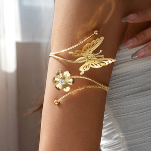 Close-up of golden arm cuff featuring a sparkling rhinestone flower and hollow butterfly detail