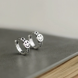 Macro shot of vintage 925 silver hoop earrings with smile face icon and carved texture
