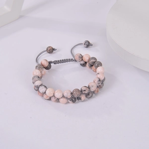 Detail of adjustable double-layer pink zebra stone beaded bracelet with woven cord