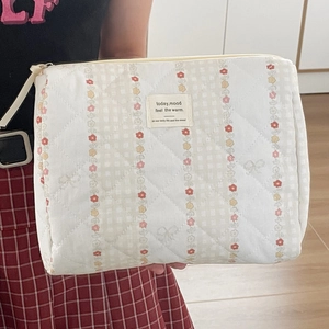 Quilted floral cosmetic bag in cream cotton held by a model for a daily organizer look