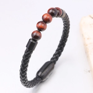 Dettaglio del bracciale in pelle nera intrecciata con perline in pietra occhio di tigre