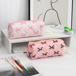 Close-up of quilted floral pencil cases with cute bow accents on a white desktop