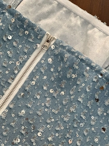 Détail du denim bleu avec paillettes argentées et fermeture éclair sur pantalon large