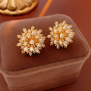 Detail of gold-plated sunflower studs with white marquise zircons on brown velvet