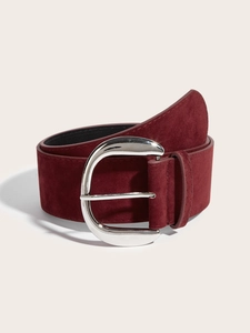 Detailed view of a wide burgundy suede belt featuring a large polished horseshoe buckle