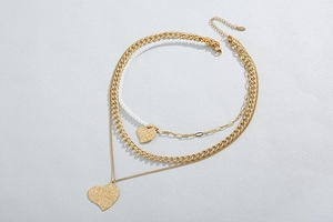 Detail of double-layer necklace featuring hammered heart pendants and pearl chain details
