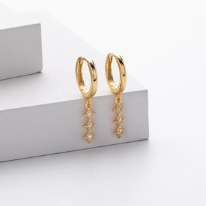 Détail de boucles d'oreilles créoles dorées avec cristaux marquise et goutte
