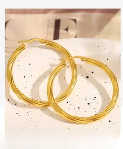 Detail of 18k gold plated twisted hoop earrings on a decorative ceramic tray