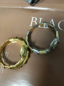 Detail of snake-shaped bangle watches in gold and two-tone finishes on magazine background