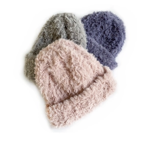 Close-up of soft faux fur knitted hats in pink, grey and purple with plush texture