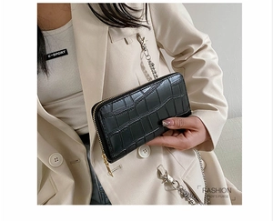 Detail showing the black crocodile pattern leather texture on a long zip-around purse