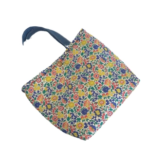 Floral print cotton lunch bag with insulated lining and blue handles on white background