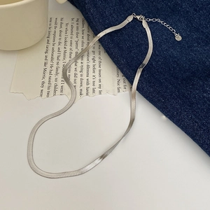 Close-up of silver snake chain necklace on denim and vintage book page background