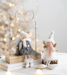 Detail of plush Christmas angel dolls with heart metal frames on round wooden bases