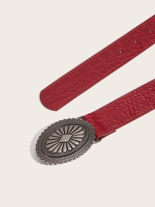 Detail of red crocodile texture leather belt with a vintage bronze floral oval buckle