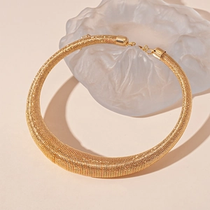 Detail view of golden torque necklace with spiral texture and lobster clasp closure