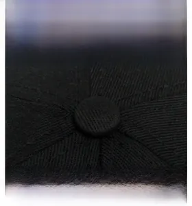 Macro detail of the top button and reinforced stitching on a black cotton baseball cap