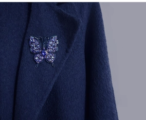Gros plan détaillé d'une broche papillon en cristal bleu sur un revers de manteau bleu